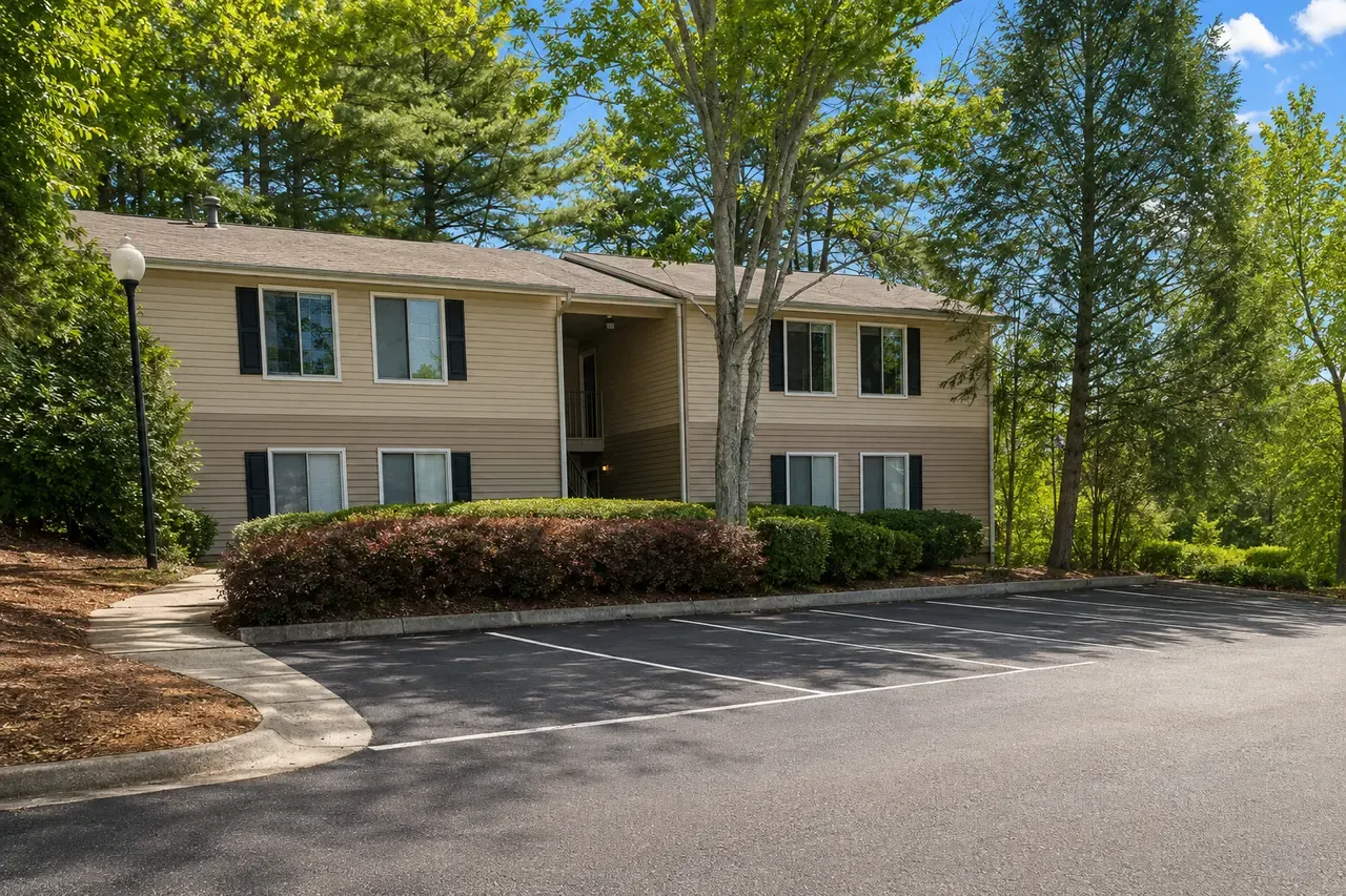 Two-story buildings under tall trees at The Woods at Windy Hill