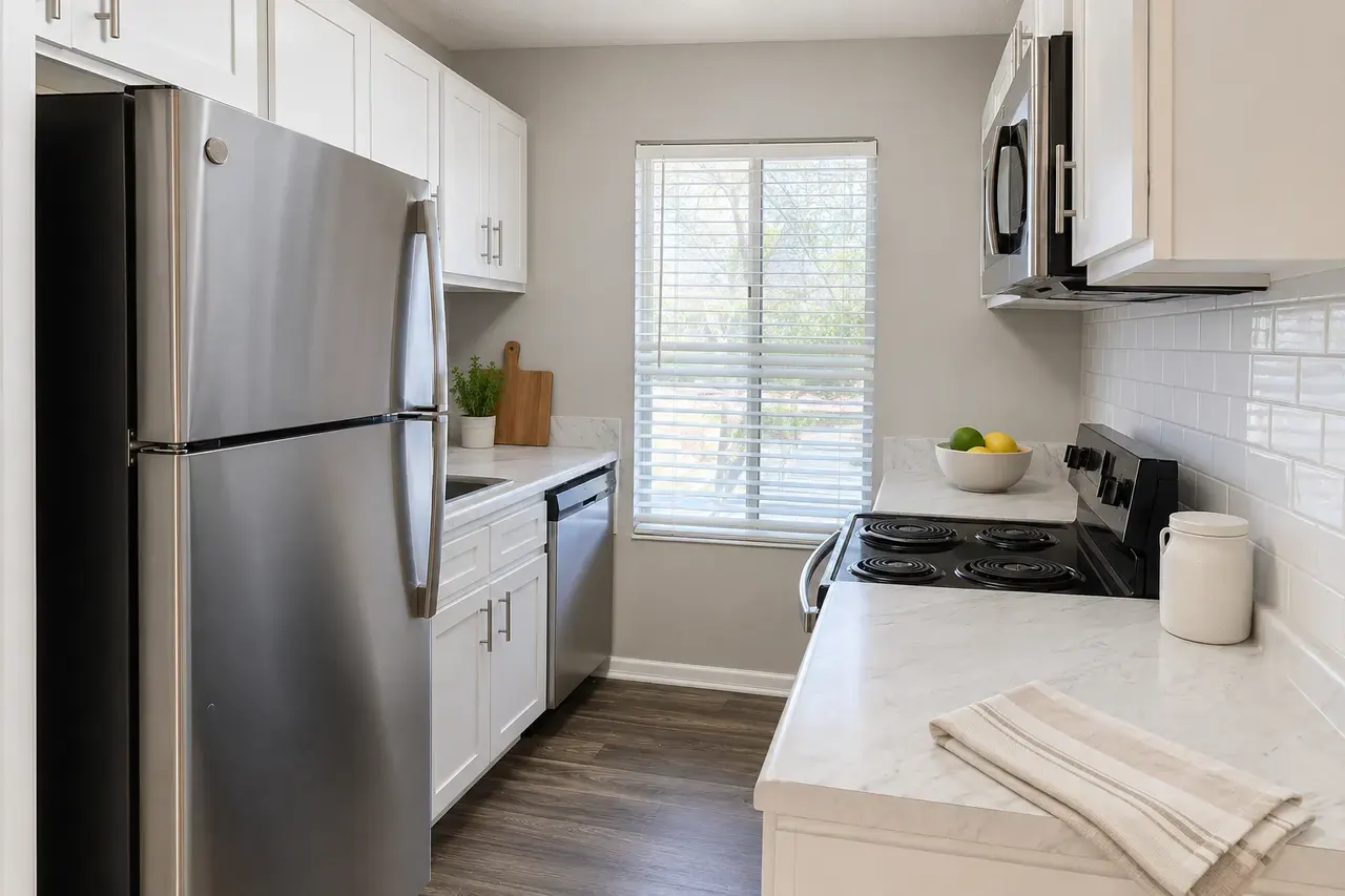 Renovated kitchen with white cabinets, stainless refrigerator, dishwasher and range, and marble-look counters